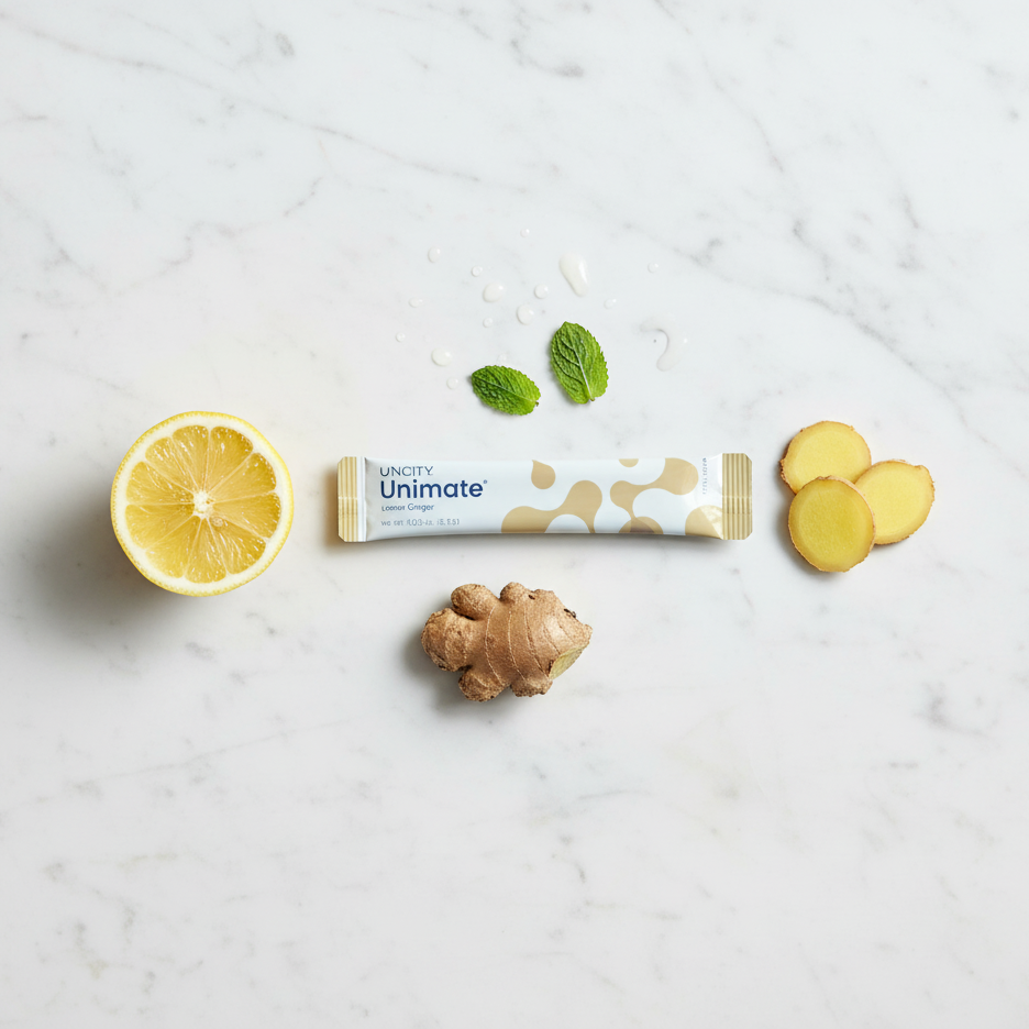 Unimate product packaging with lemon, ginger, and mint leaves on a marble surface