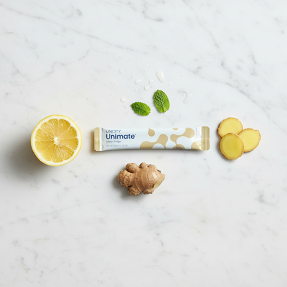Unimate product packaging with lemon, ginger, and mint leaves on a marble surface